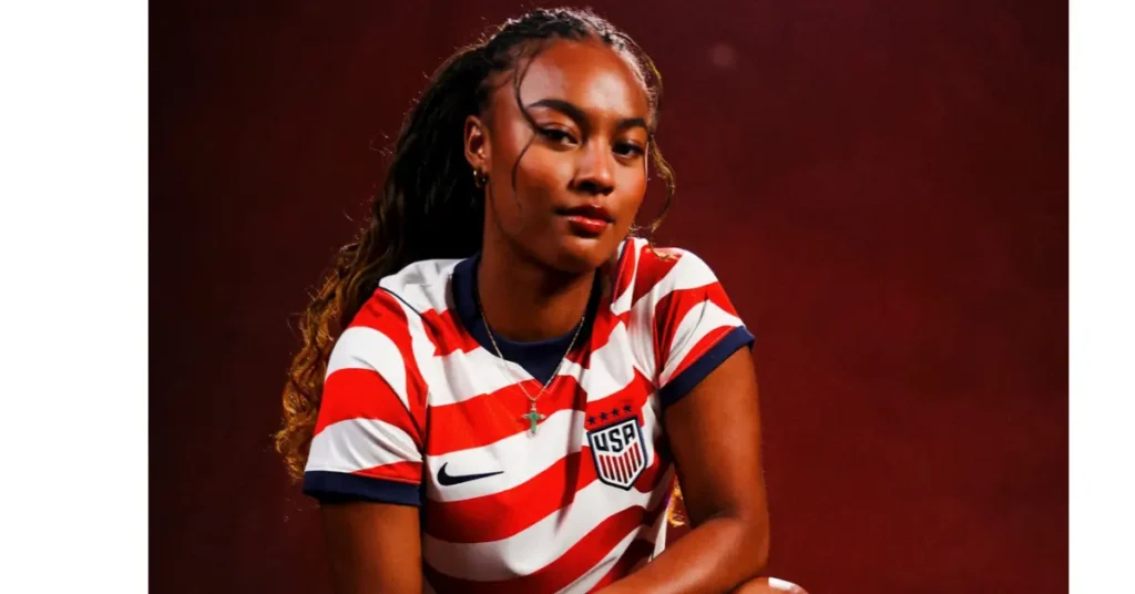 USWNT defender Naomi Girma crouching with a soccer ball, showcasing the full new home kit