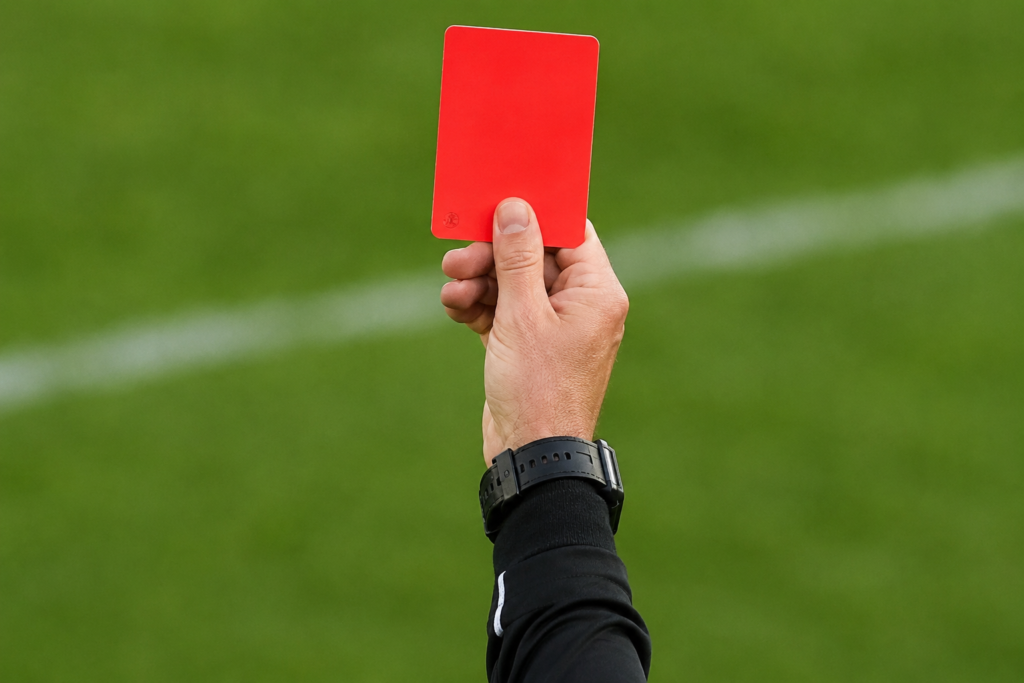 A referee holding up a red card during a chaotic women's soccer match.